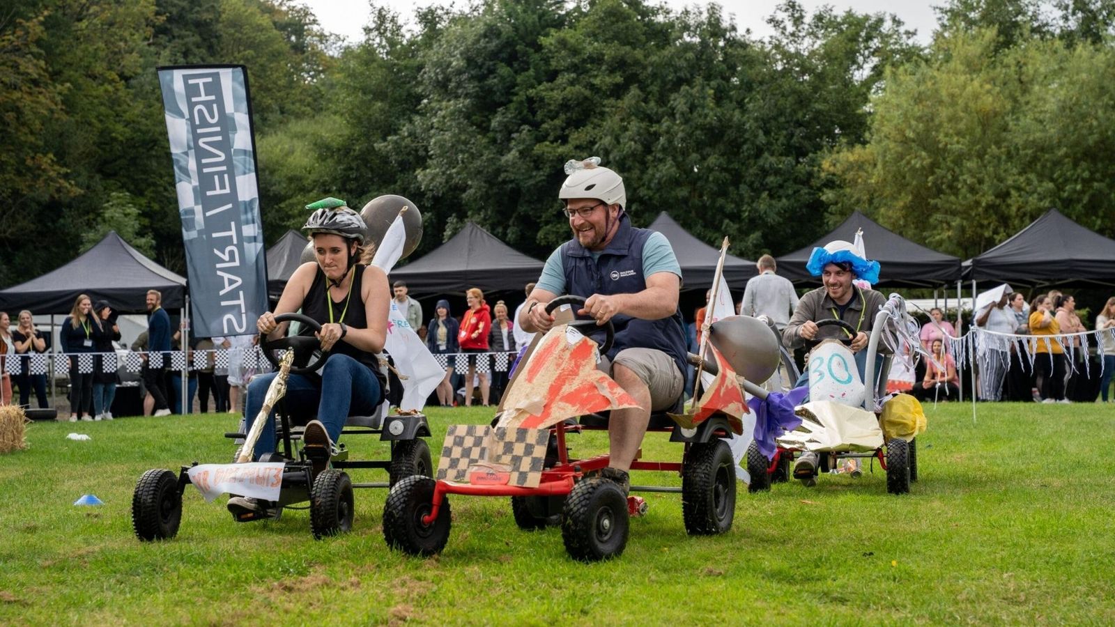 Dos karts de pedales cruzando la meta con el público animando detrás